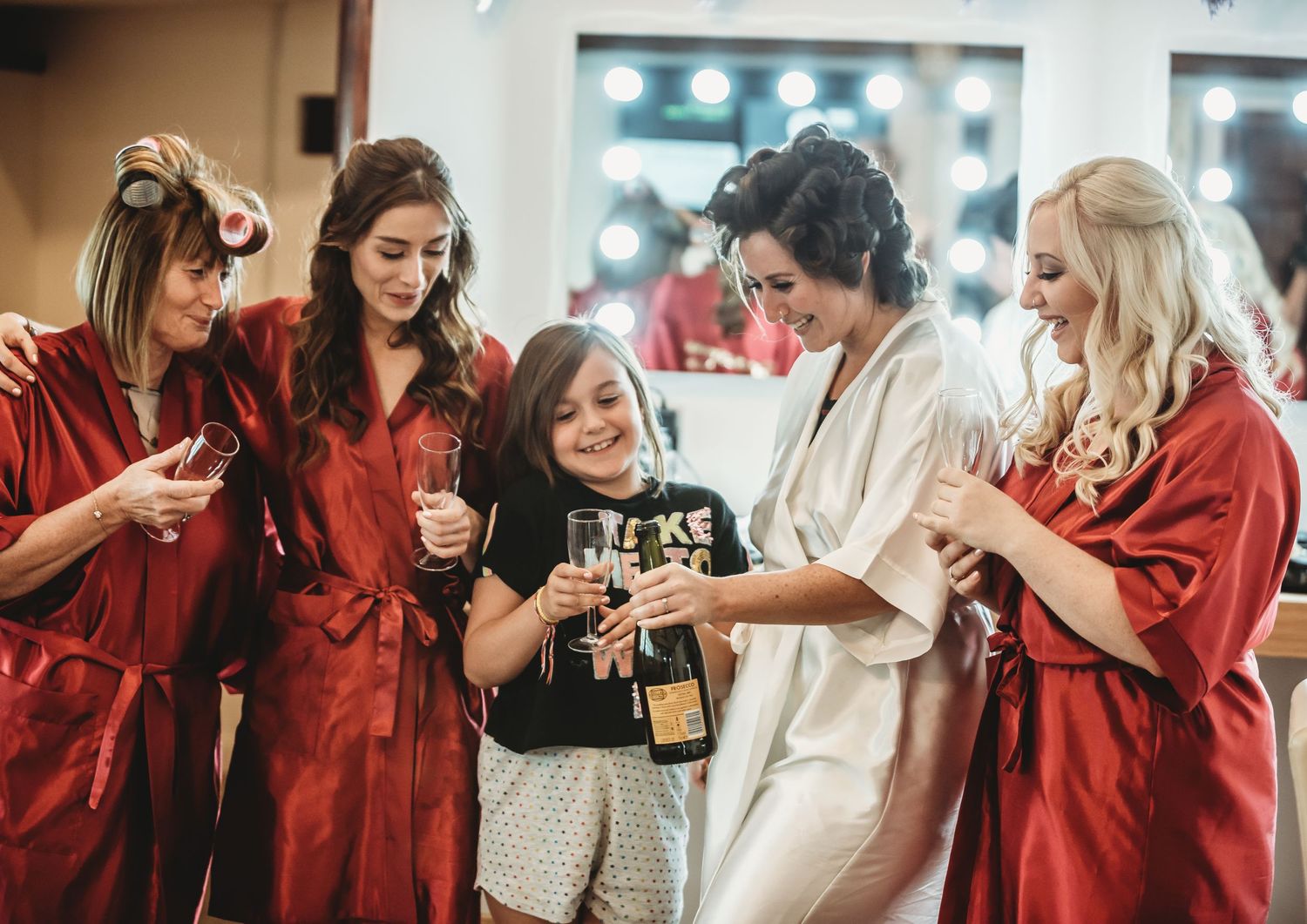 A group in red getting ready for a celebration together as they hold champagne glasses and share cheerful moments.
