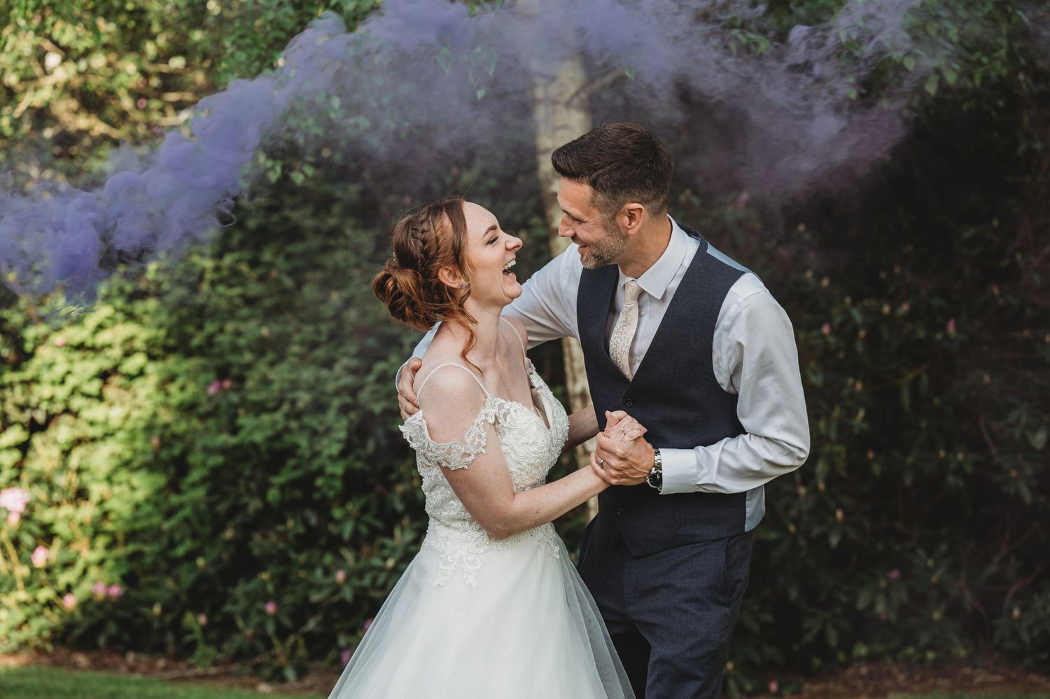 A couple shares a romantic dance moment outdoors with purple smoke effects in the background.