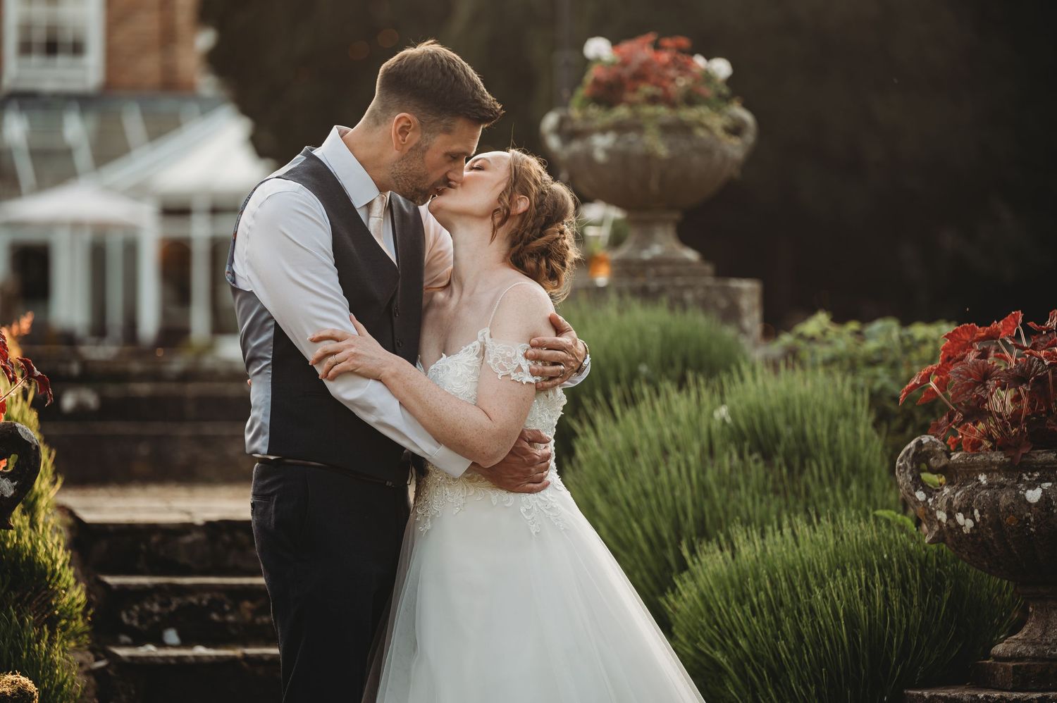 A romantic wedding moment captured in a garden setting with stone steps and decorative planters.
