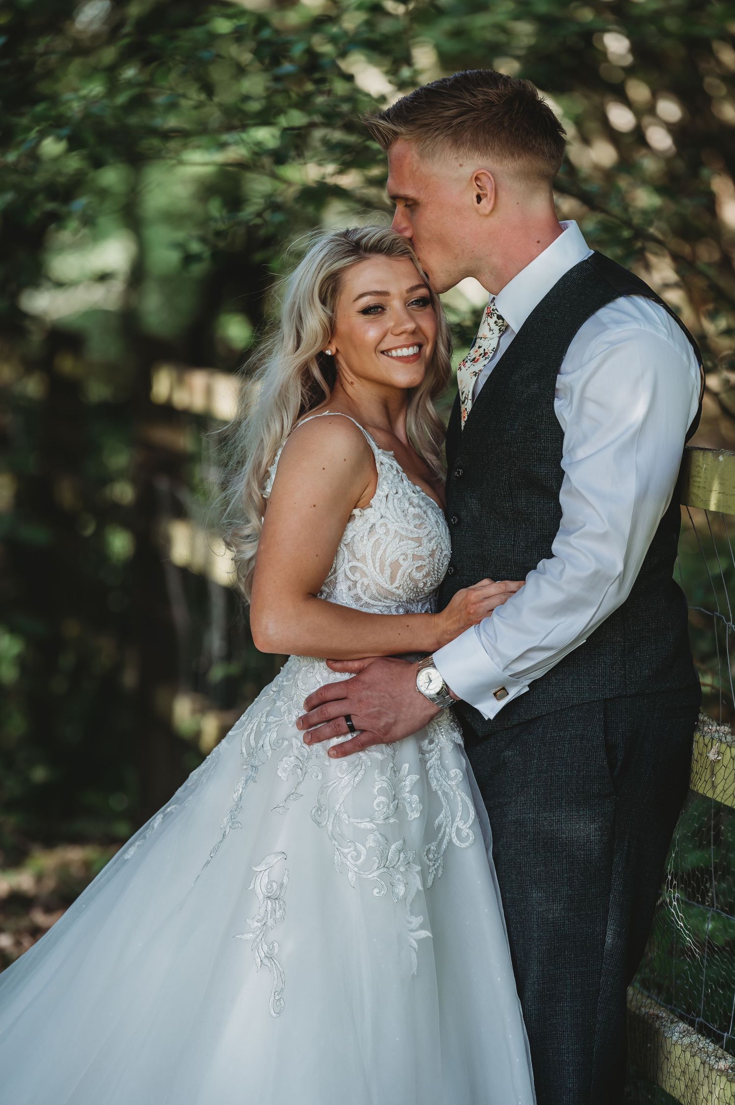 A romantic wedding moment captured in a garden setting with natural lighting and elegant attire.