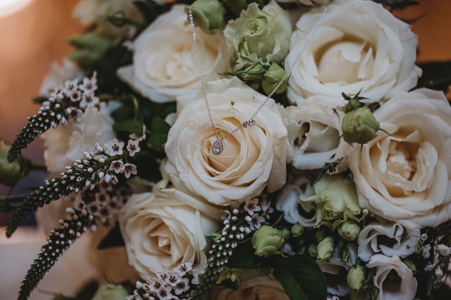 A romantic cream rose wedding bouquet featuring delicate white roses and wispy green foliage accents.