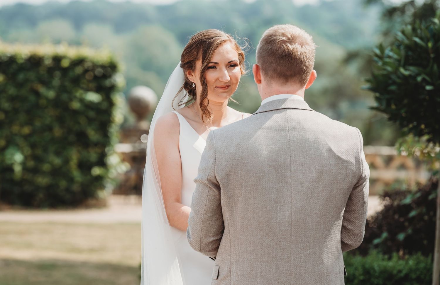 A bride and groom share an intimate moment during their outdoor wedding ceremony in a garden setting.