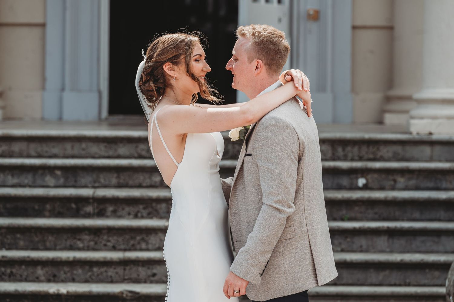 A couple shares an intimate moment during their wedding photoshoot on elegant stone steps.