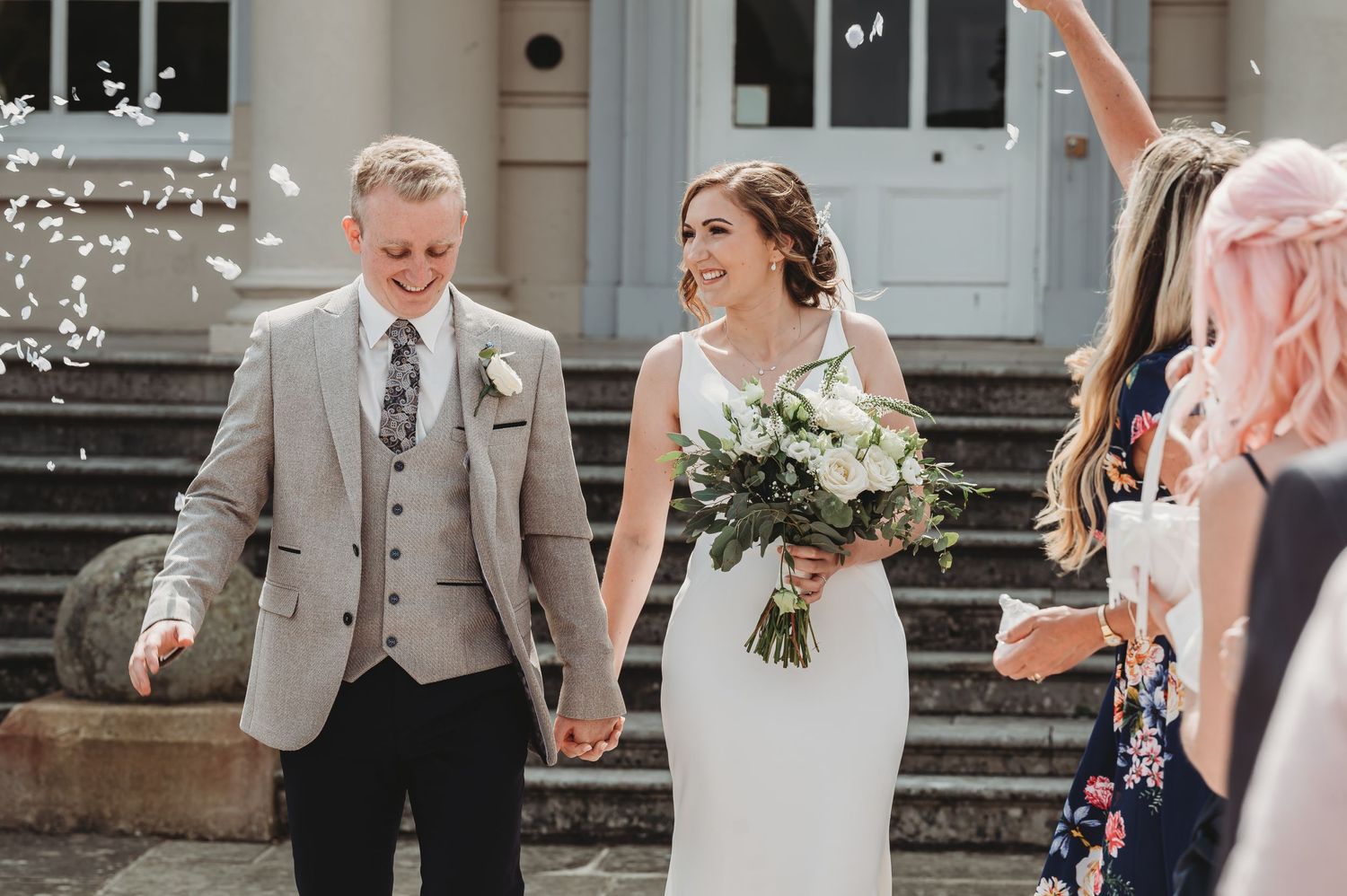 Newlyweds exit their wedding ceremony while guests throw confetti on church steps.