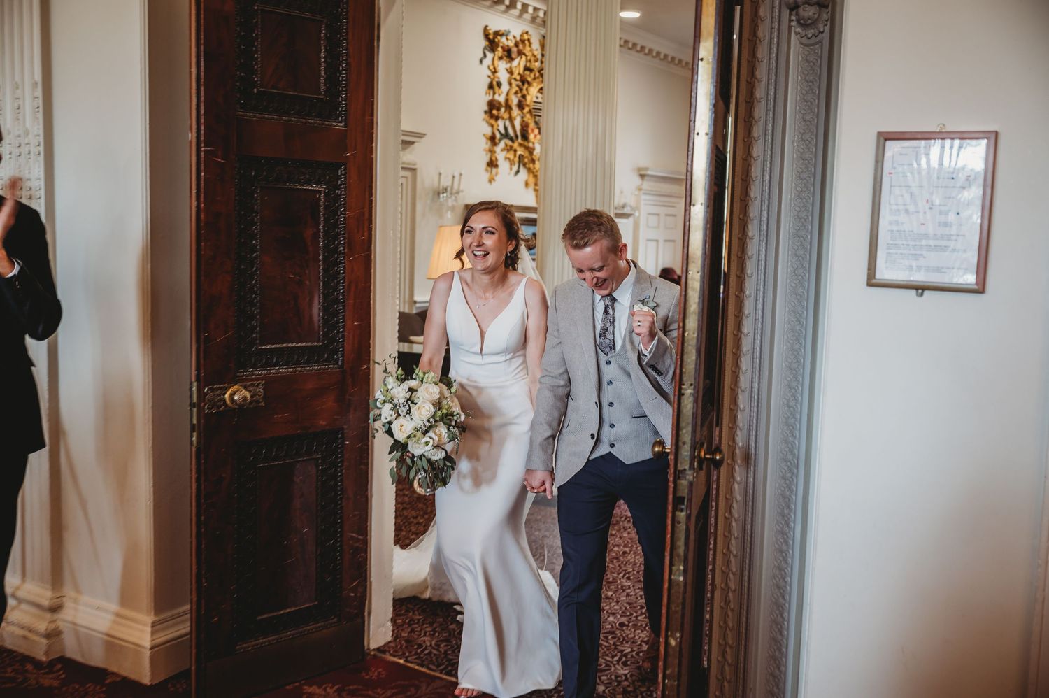 A happy couple walks through an elegant venue doorway during their wedding celebration.