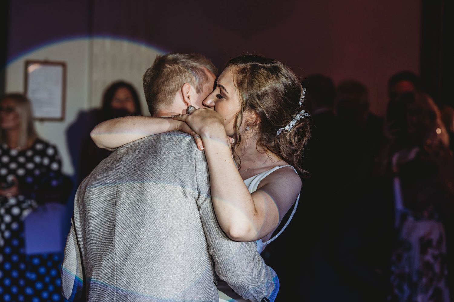 A couple shares an intimate first dance during their wedding reception in a dimly lit venue.