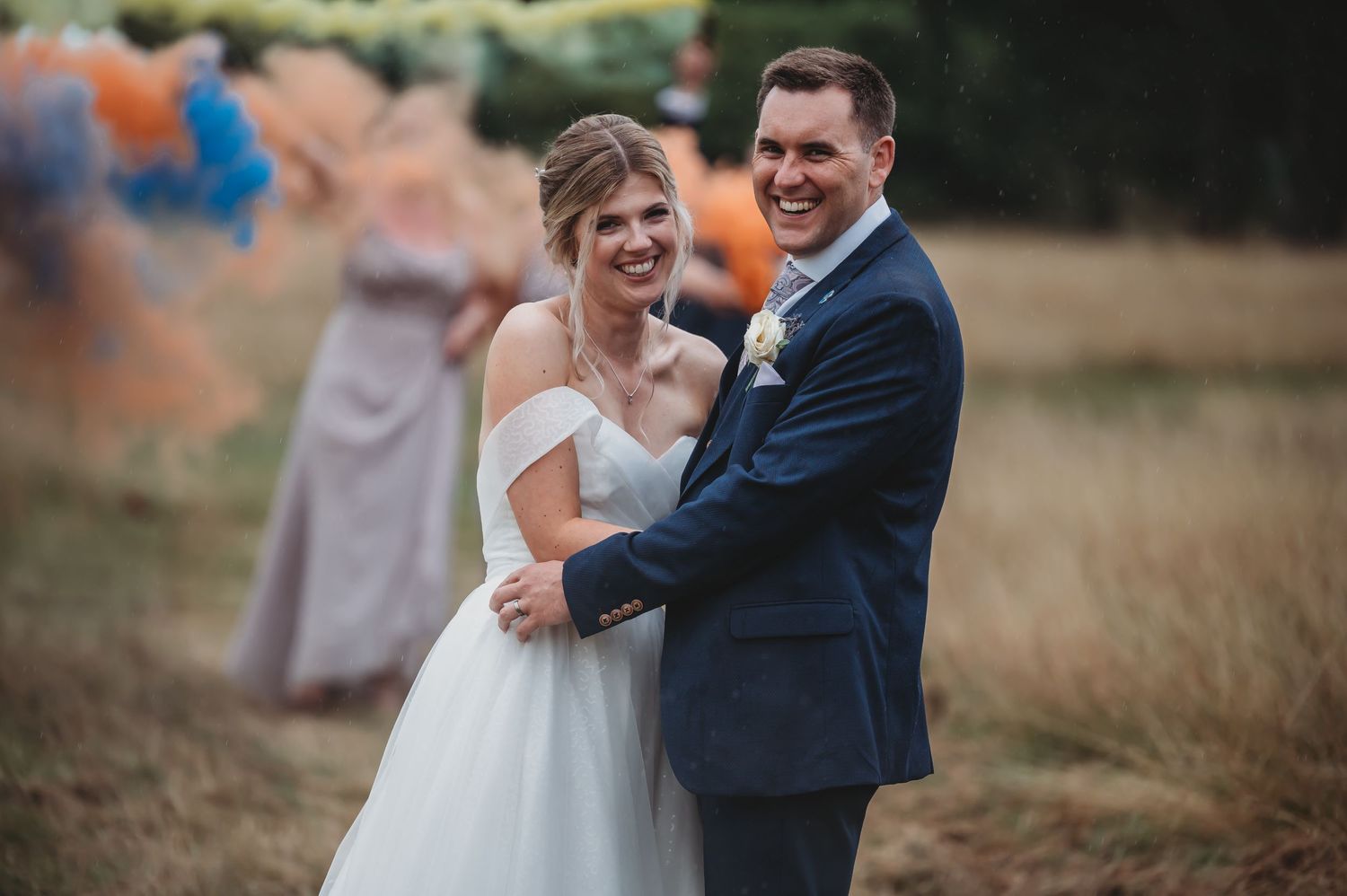 A couple shares a joyful moment in a rustic field setting at their outdoor wedding celebration.