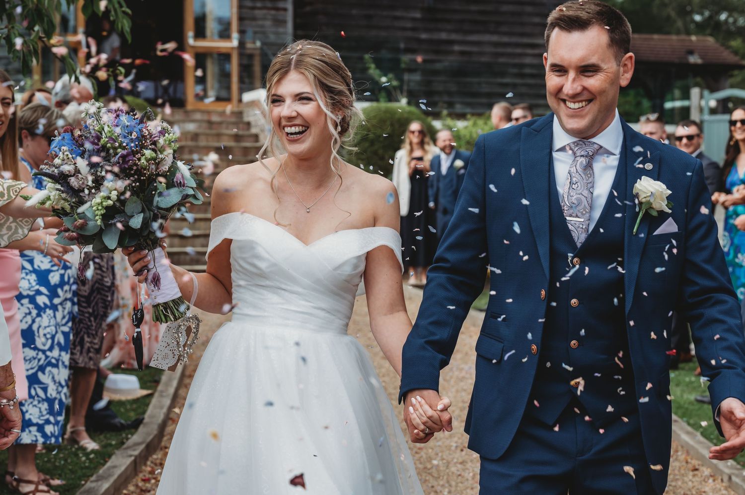 A joyful wedding celebration with confetti flying as a couple walks together in wedding attire.