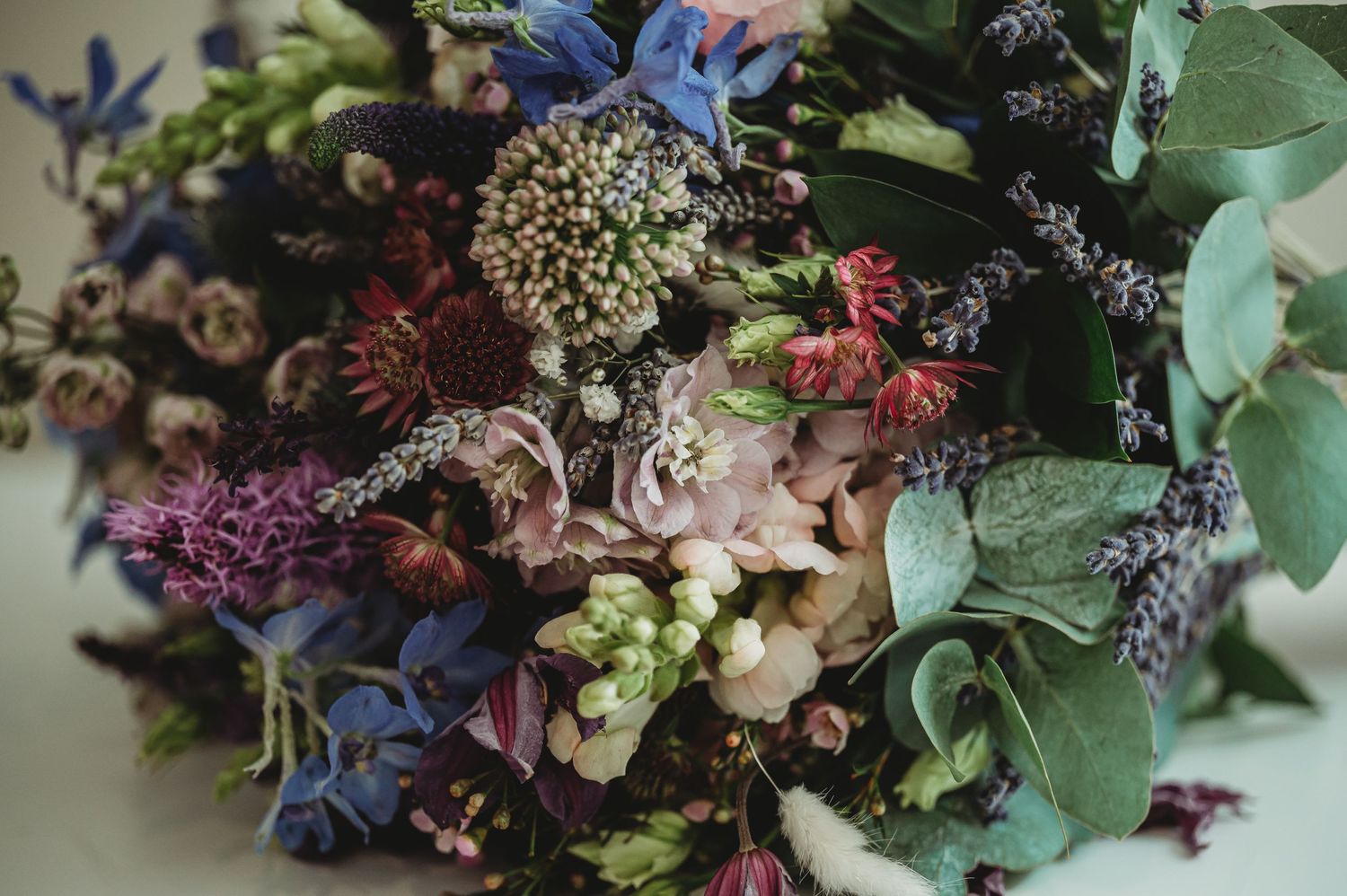 Close-up of vibrant wedding bouquet with mixed flowers in purple and blue tones.