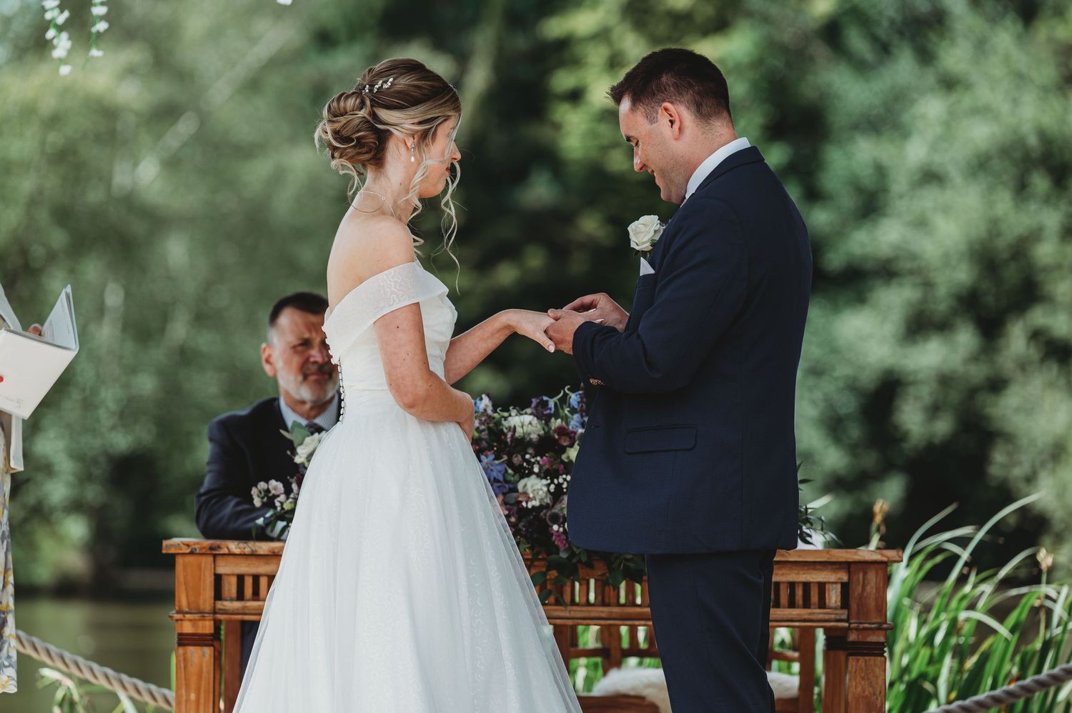An outdoor wedding ceremony under trees with classic white and navy attire.