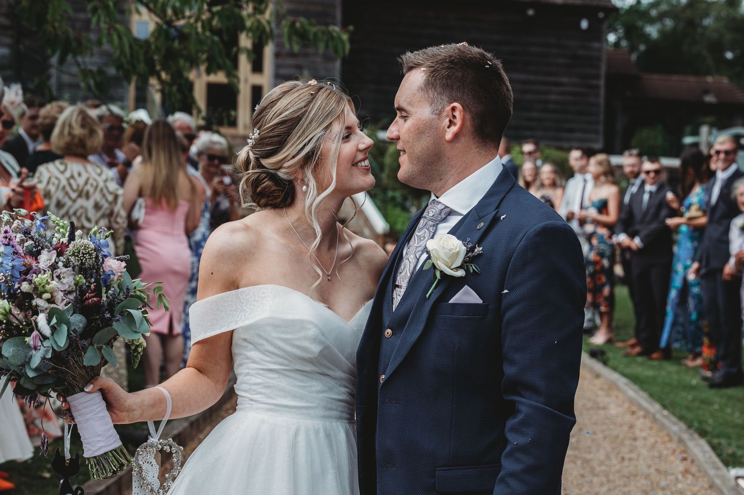 A couple shares a romantic moment during their outdoor garden wedding ceremony surrounded by guests.