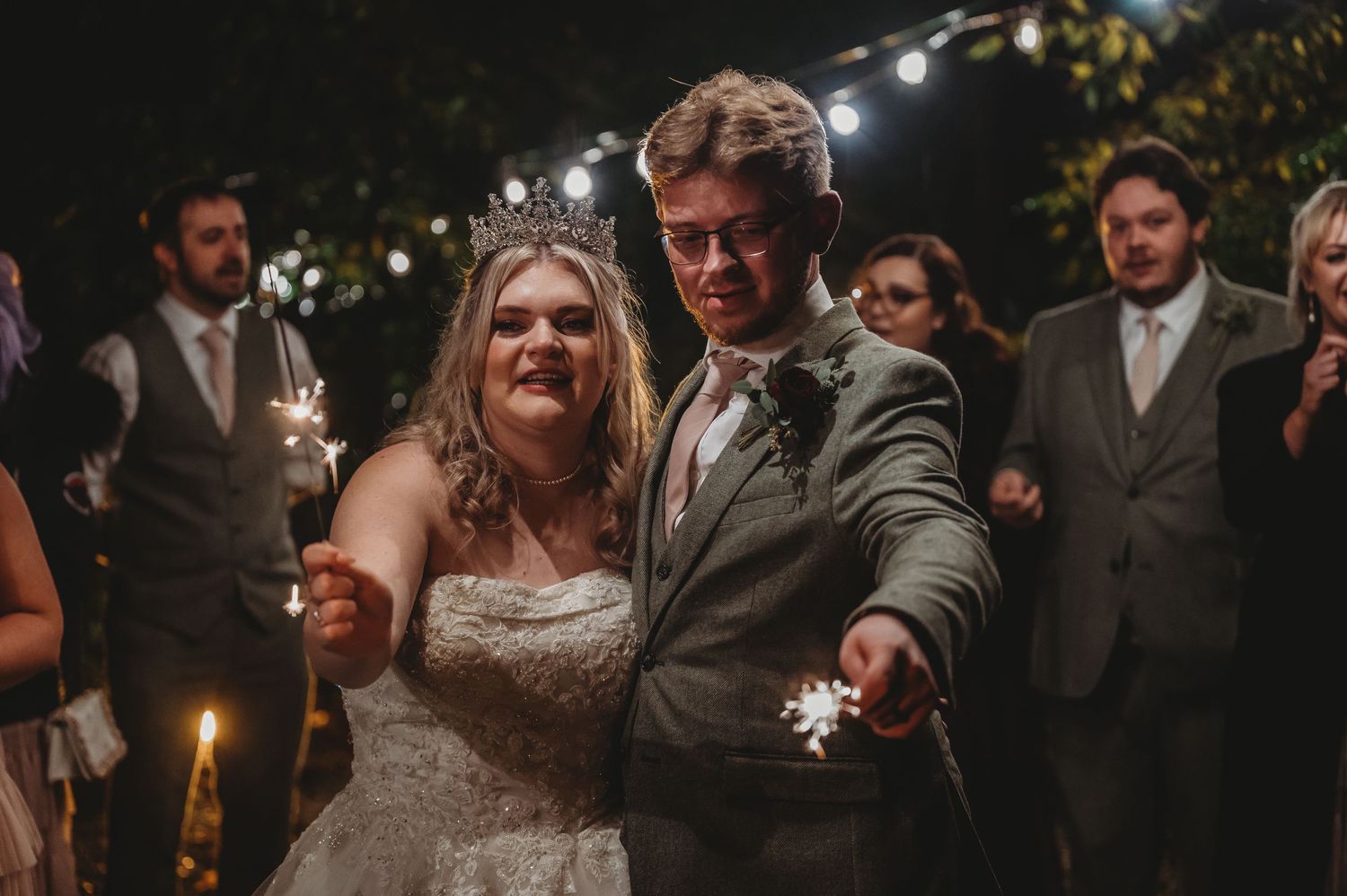 Couple dancing together with sparklers during nighttime wedding celebration.