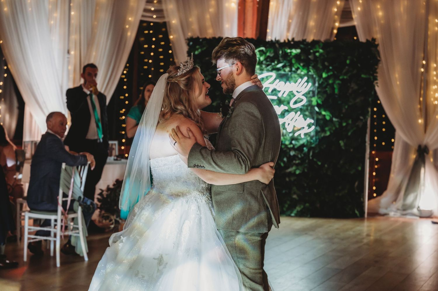 Wedding couple's first dance surrounded by fairy lights and white drapery in an elegant venue.