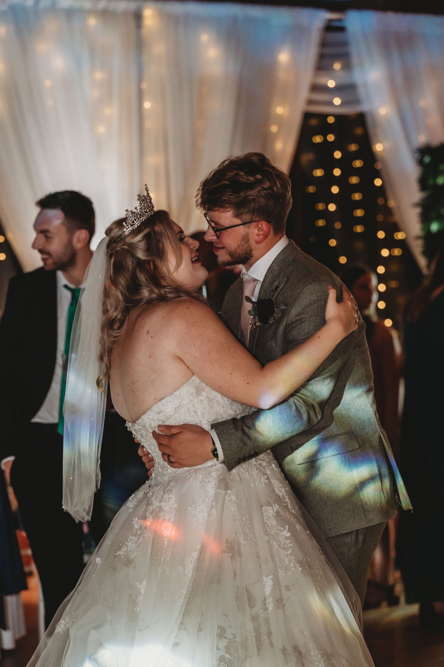 Romantic first dance at a wedding reception with twinkle lights and white draping in the background.