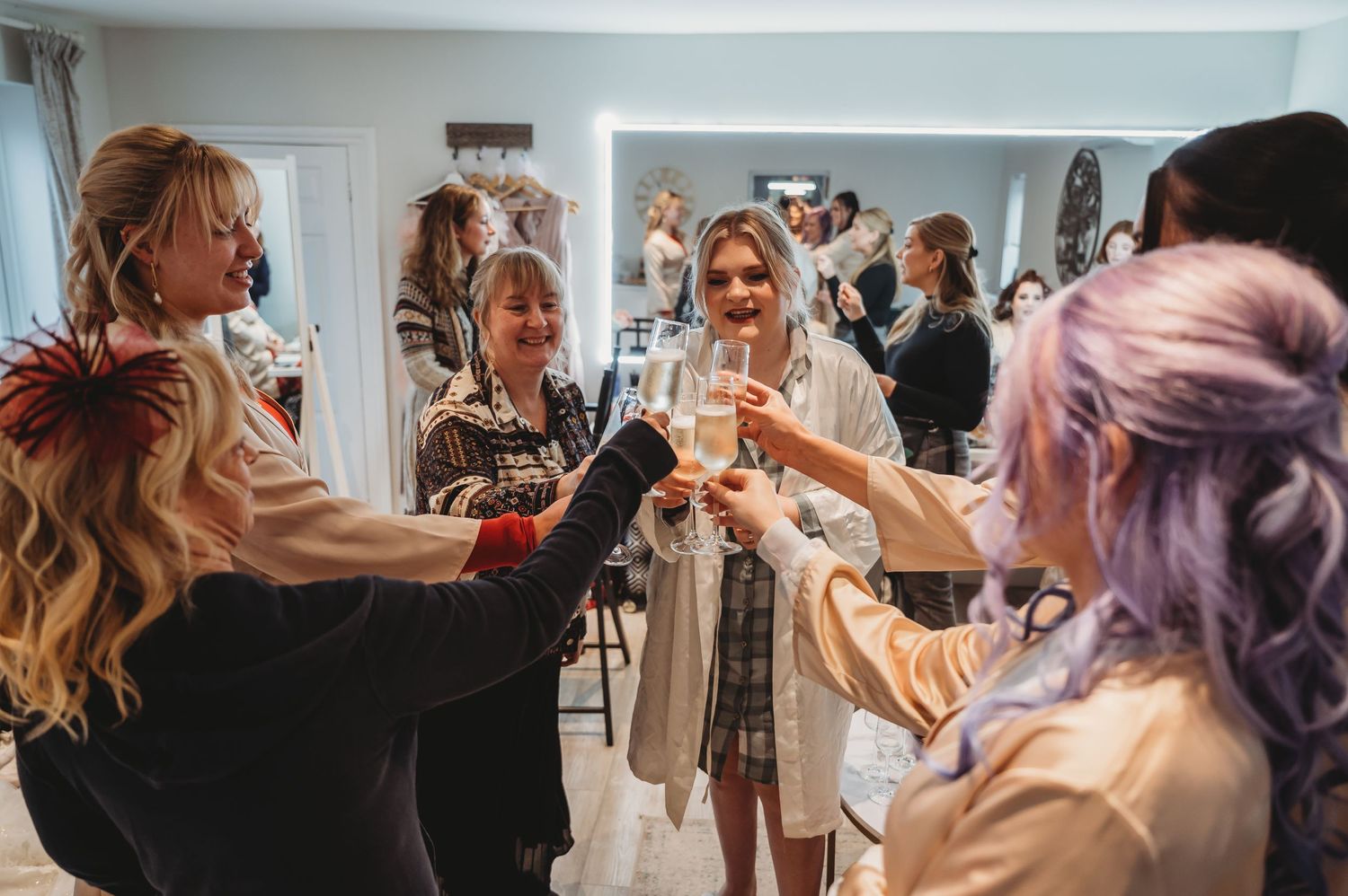 Wedding celebration with guests toasting and raising glasses in a bright indoor setting.