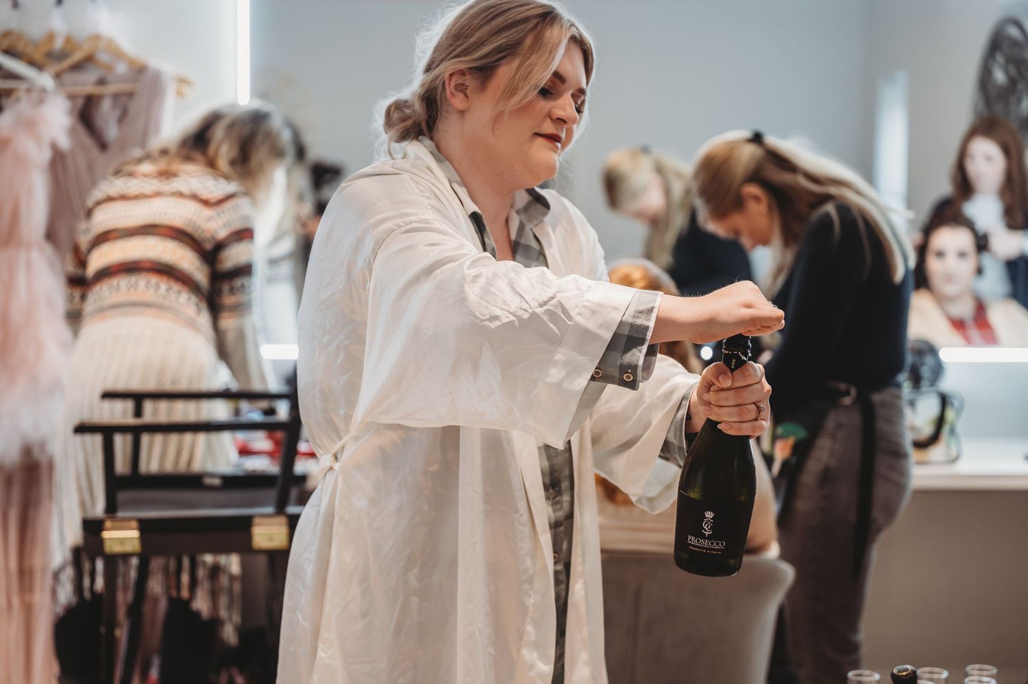 A person in white pouring a drink during what appears to be a wedding preparation event.