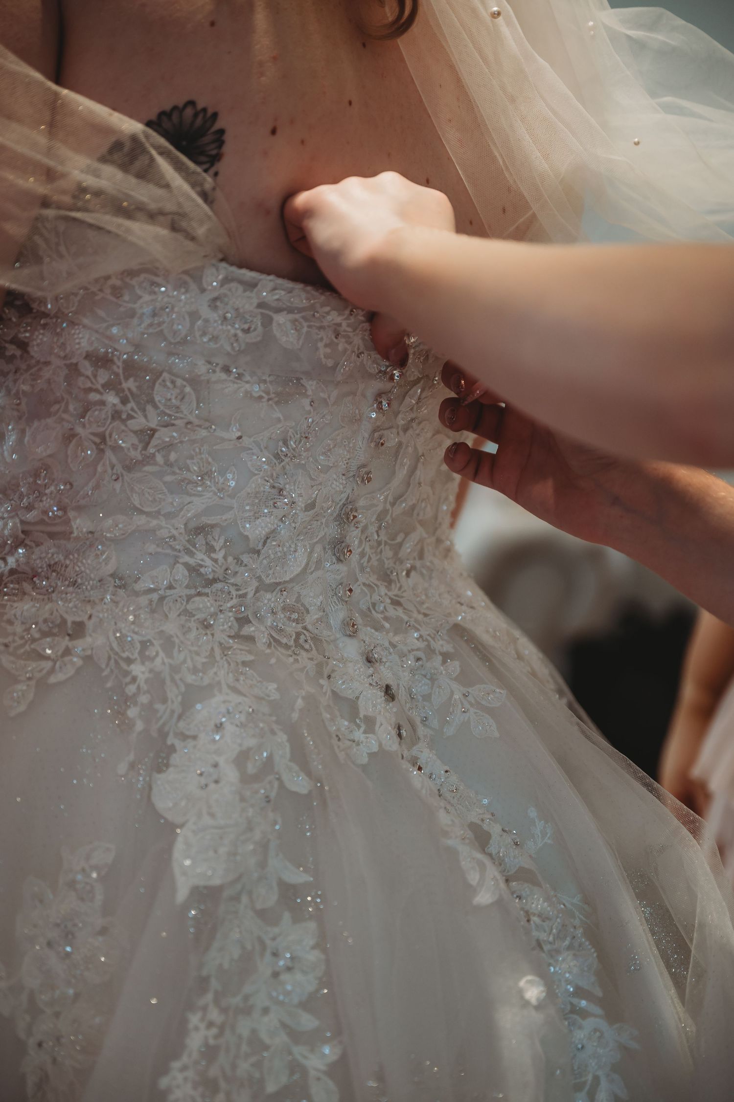 Close-up detail of intricate lace and beadwork on a white wedding dress.