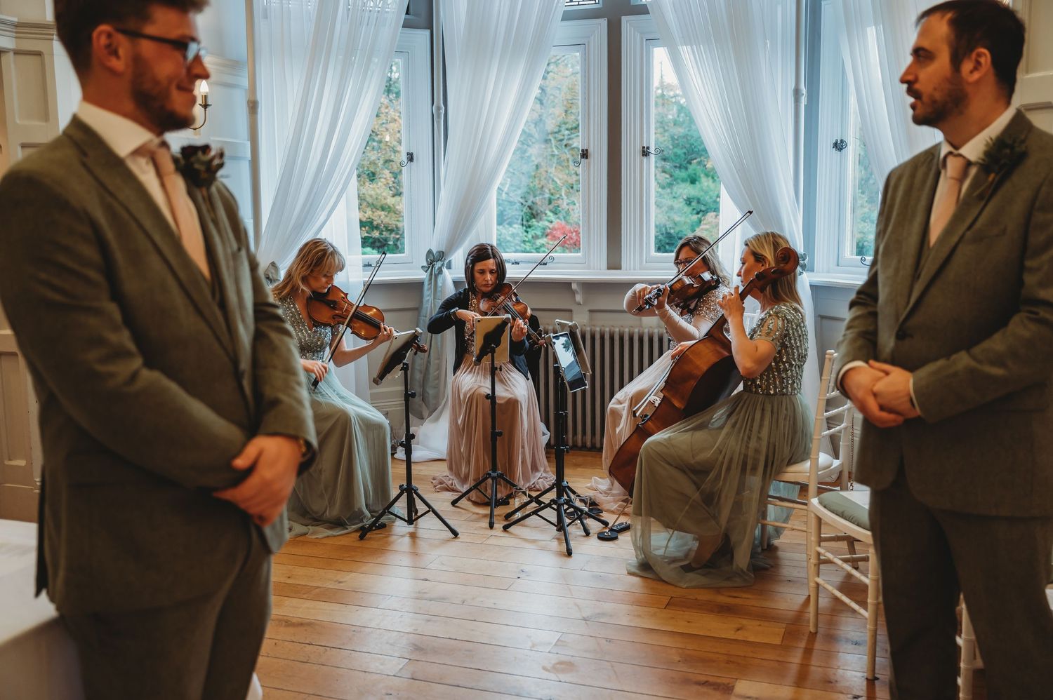 String quartet performs during wedding ceremony while attendants look on.