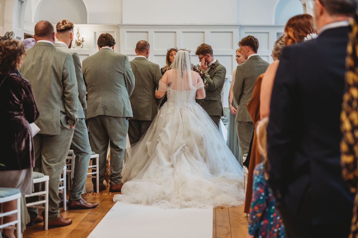 Wedding ceremony in progress showing a flowing white dress train down the center aisle.