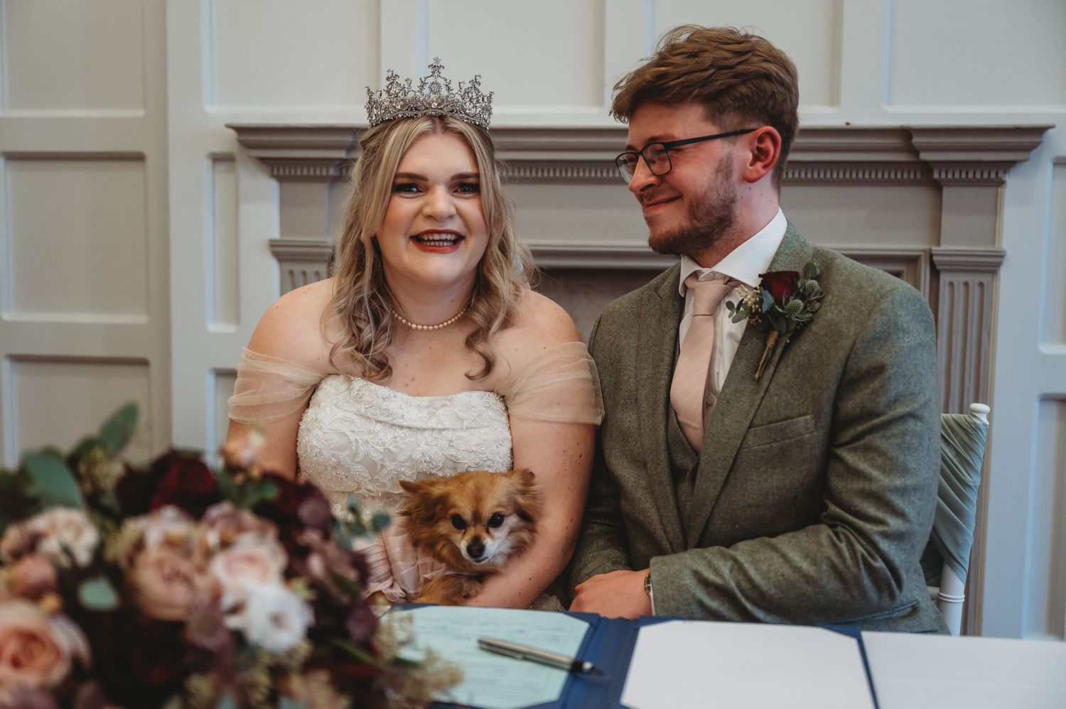 Wedding couple shares a joyful moment while signing documents at an elegant ceremony venue.