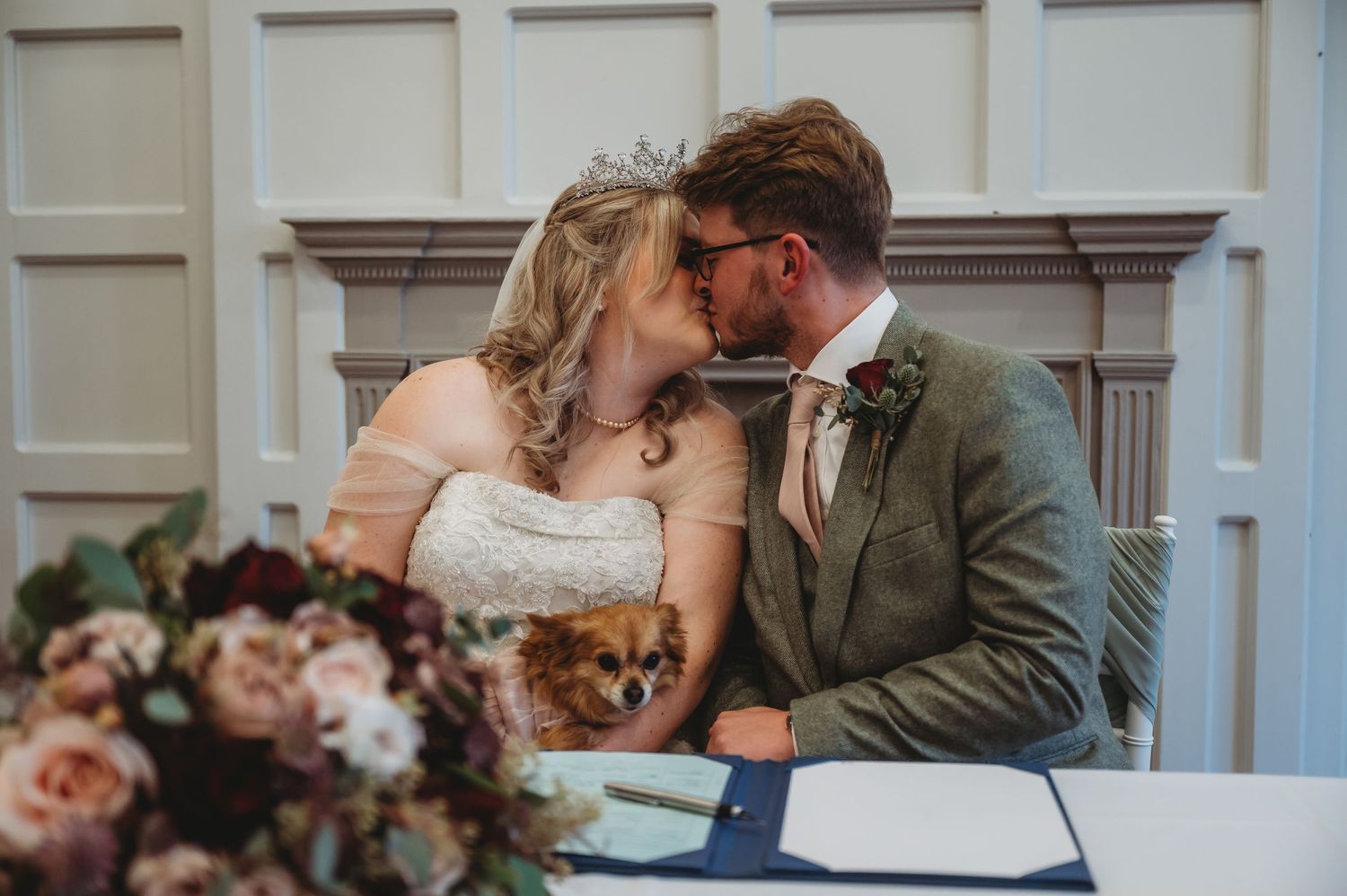 Romantic moment during wedding ceremony signing with floral arrangement in foreground.