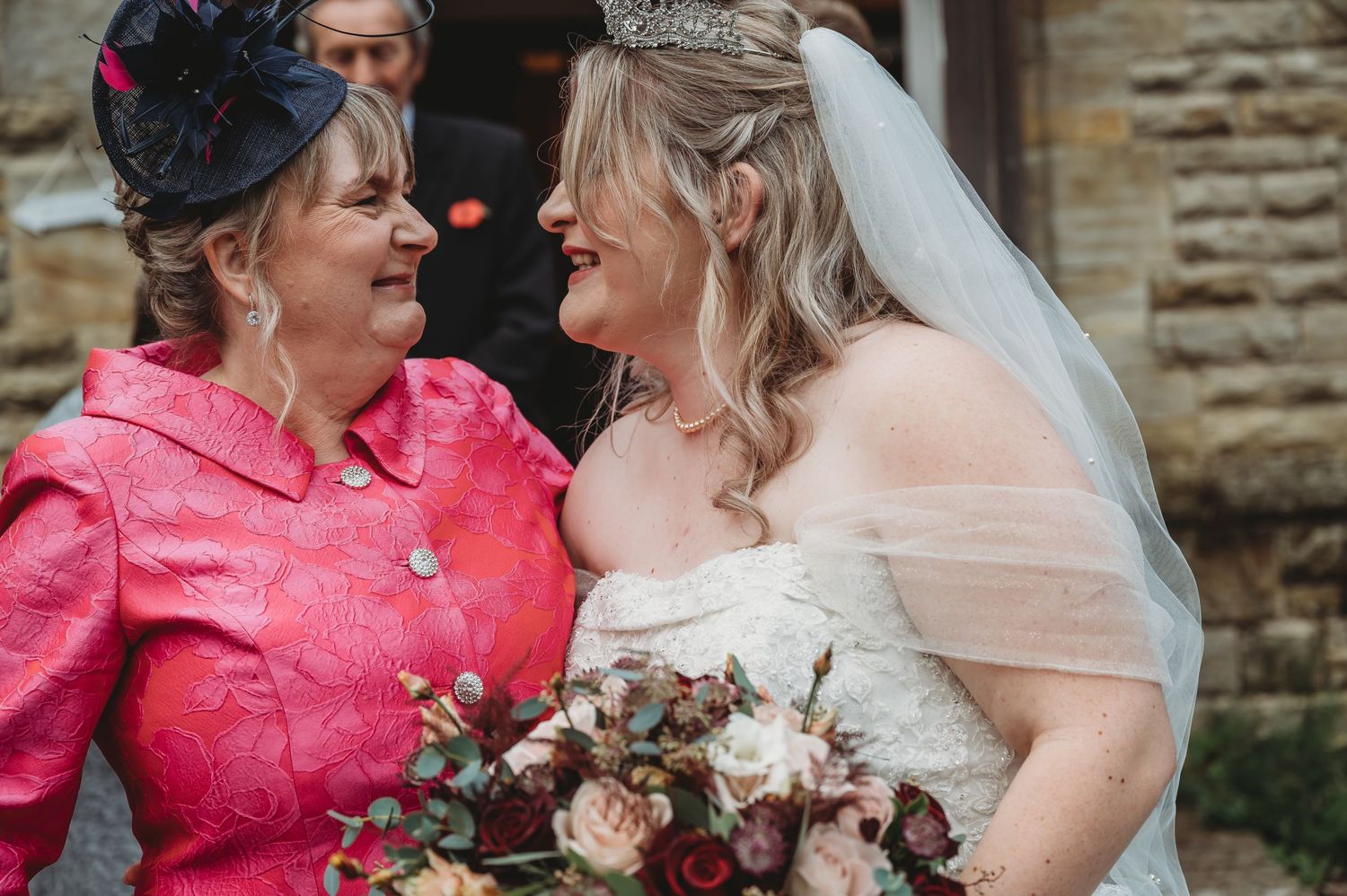 Intimate moment captured between two women at wedding with bouquet.