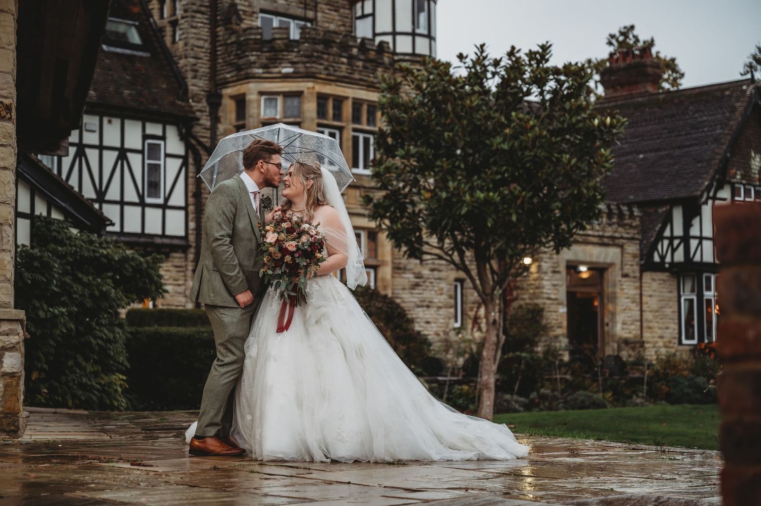 Romantic castle wedding portrait with Tudor-style architecture and string lights overhead.