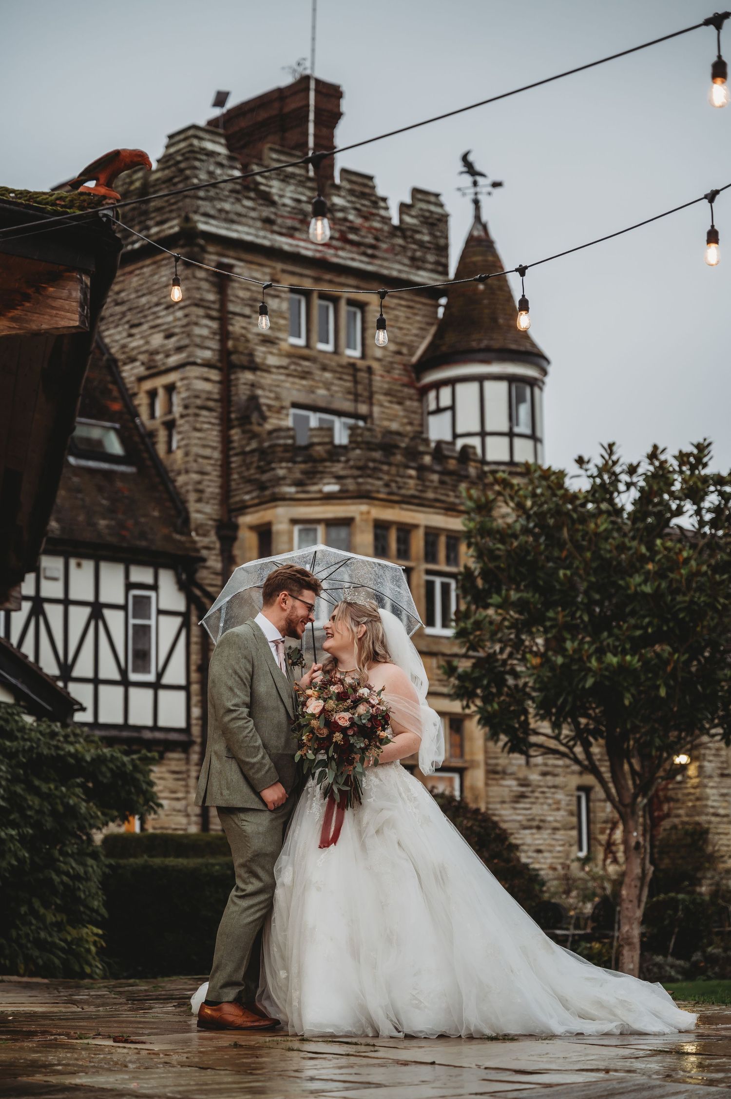 Wedding photography at castle featuring Tudor architecture and hanging string lights.