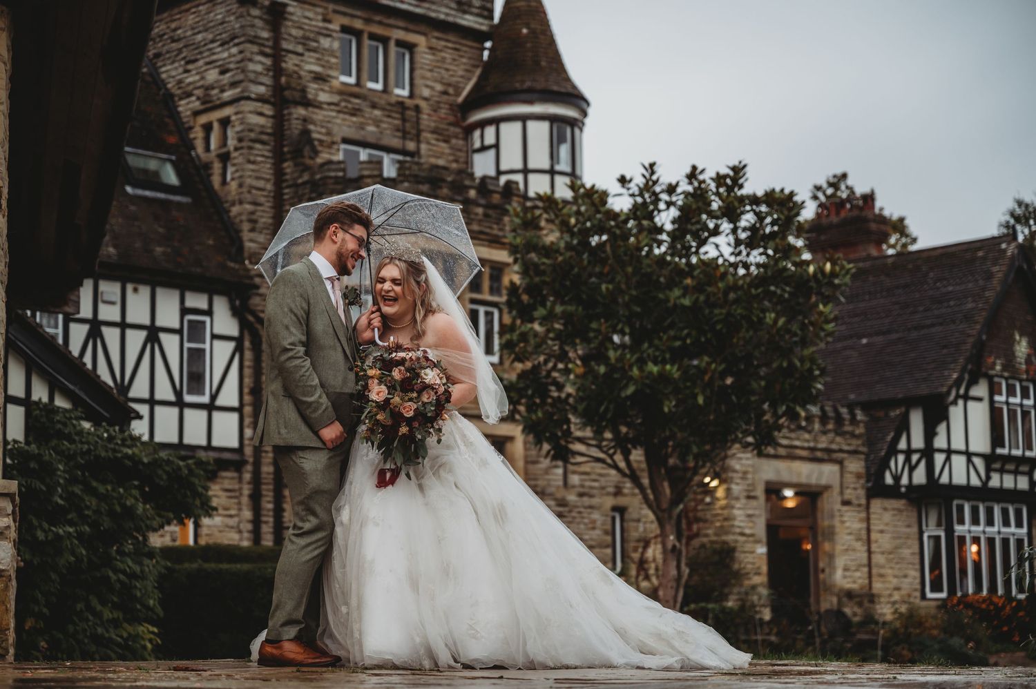 Romantic wedding portrait against stone castle backdrop with Tudor-style architecture.