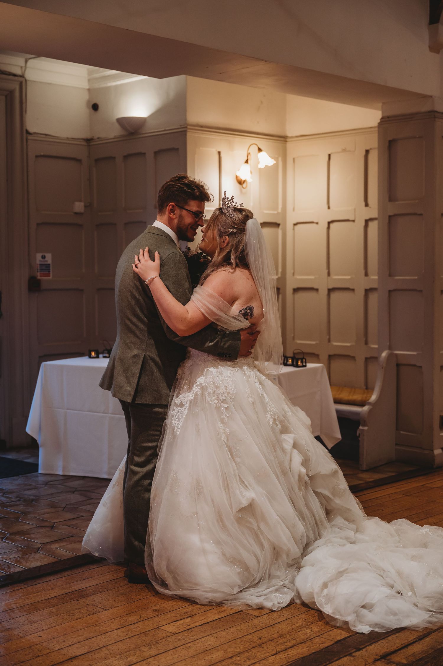 A romantic dance moment captured in an elegant wood-paneled venue with a flowing white wedding dress.