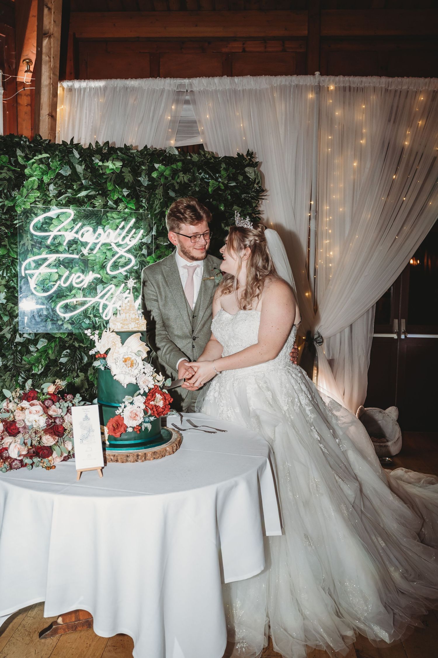 A romantic moment shared by newlyweds next to their tiered green wedding cake with floral decorations.