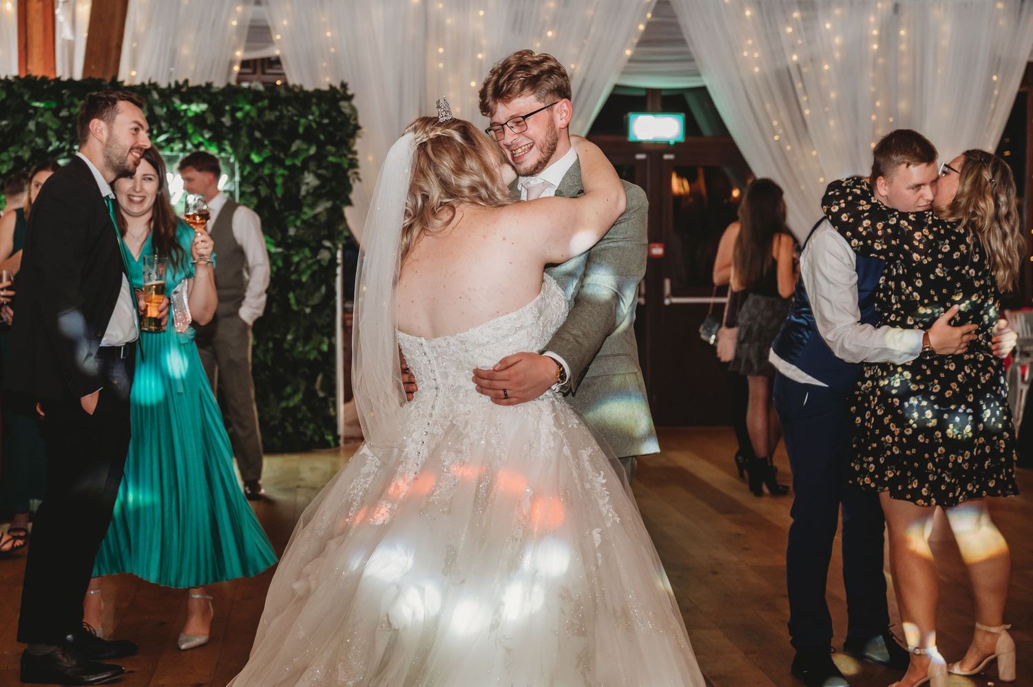 A couple shares their first dance under twinkling lights at their wedding reception.