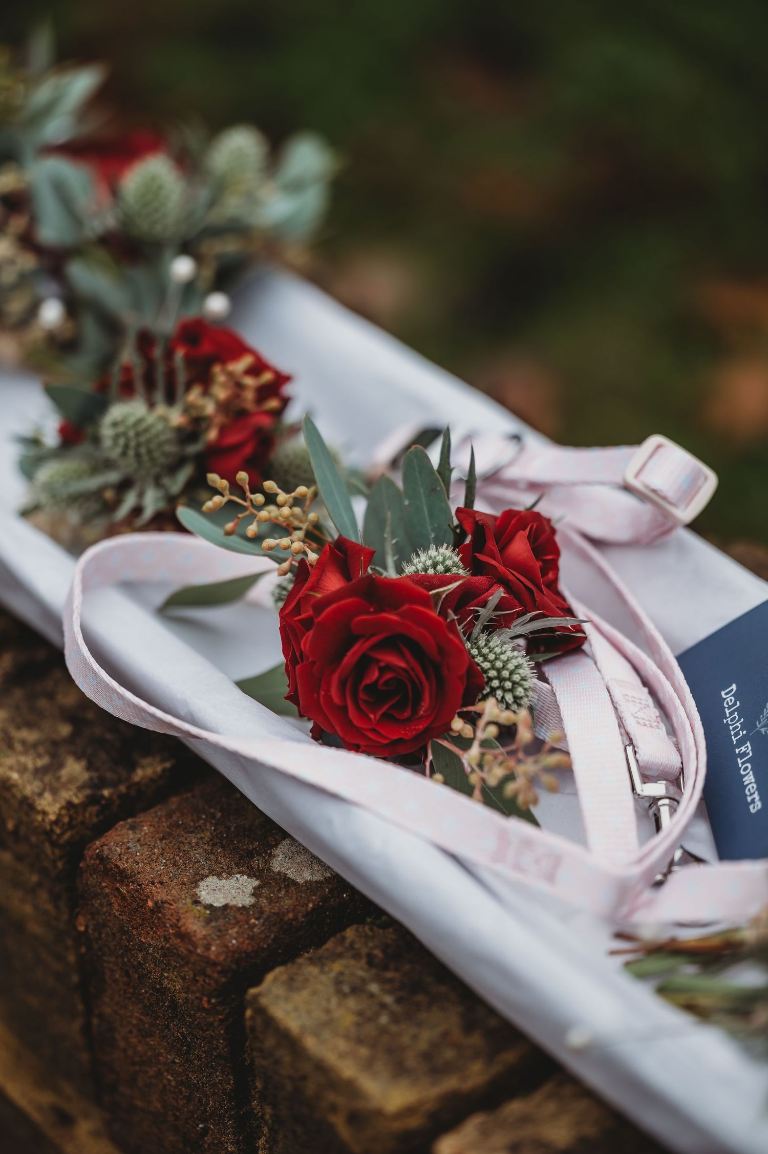 Red roses and greenery tied with pink ribbon create an elegant wedding corsage.