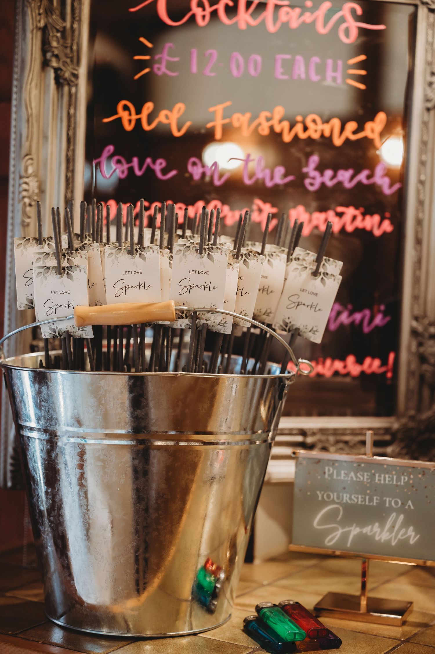 Vintage cocktail station with silver ice bucket and sparkler sign at a wedding bar.