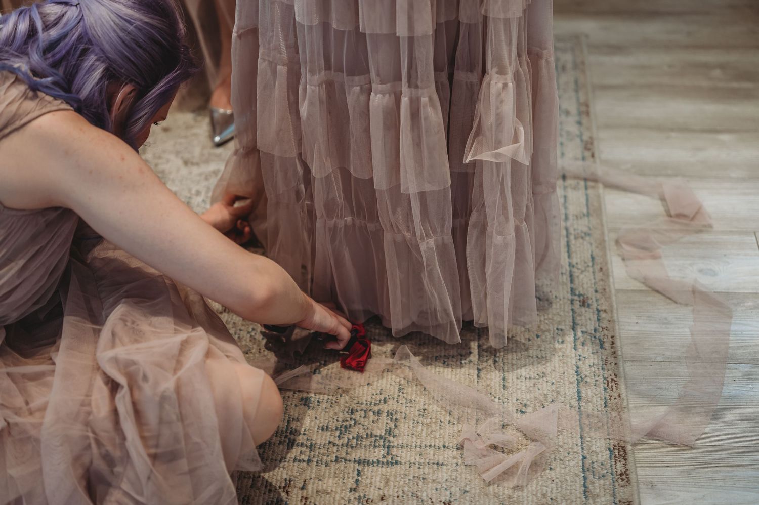 Detailed shot of hands adjusting the hem of a dress against a patterned floor.