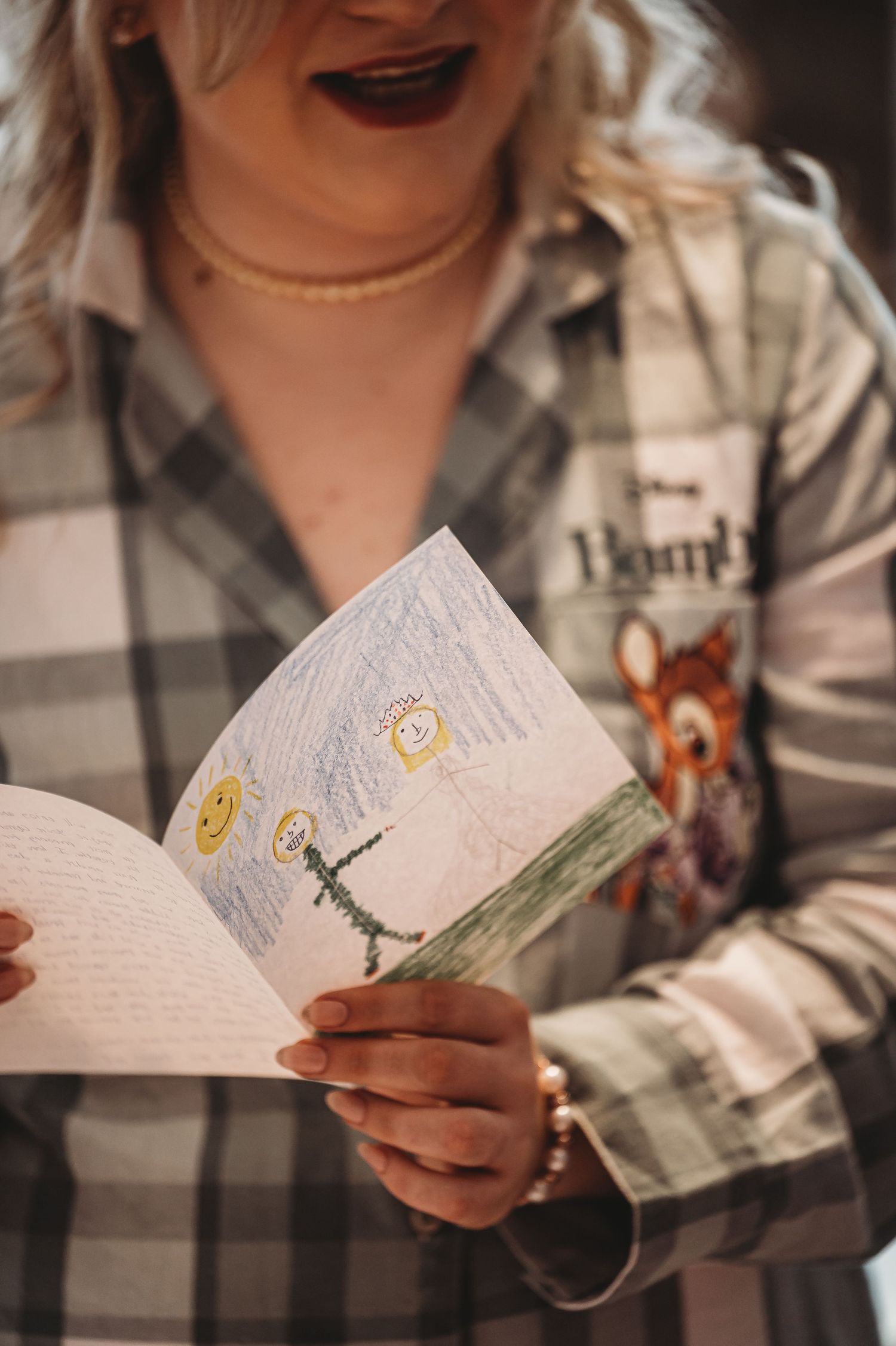Close-up of hands holding an open book with hand-drawn illustrations featuring yellow hearts.