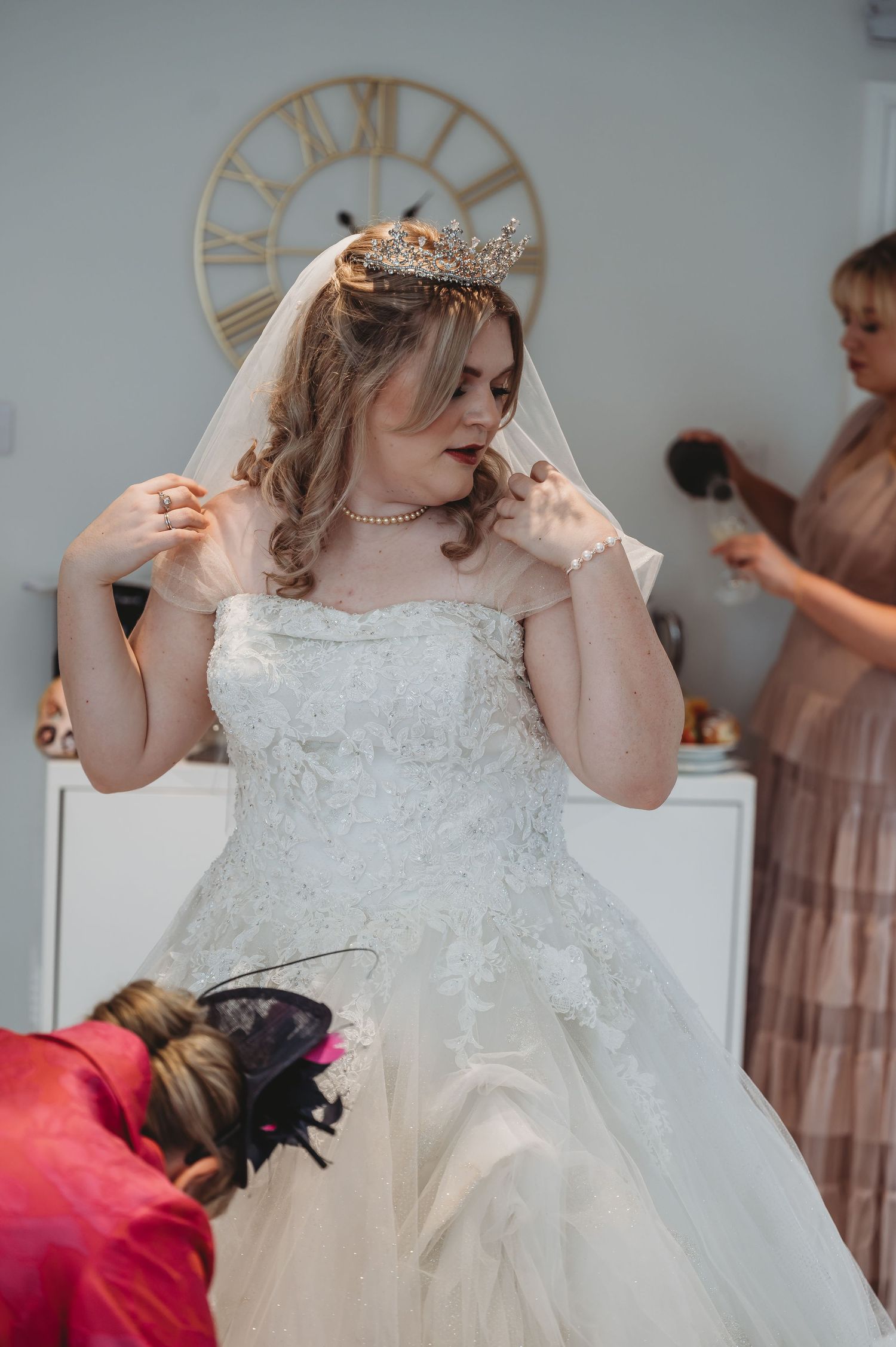 A close-up of a bride adjusting her veil beneath a large decorative wall clock.