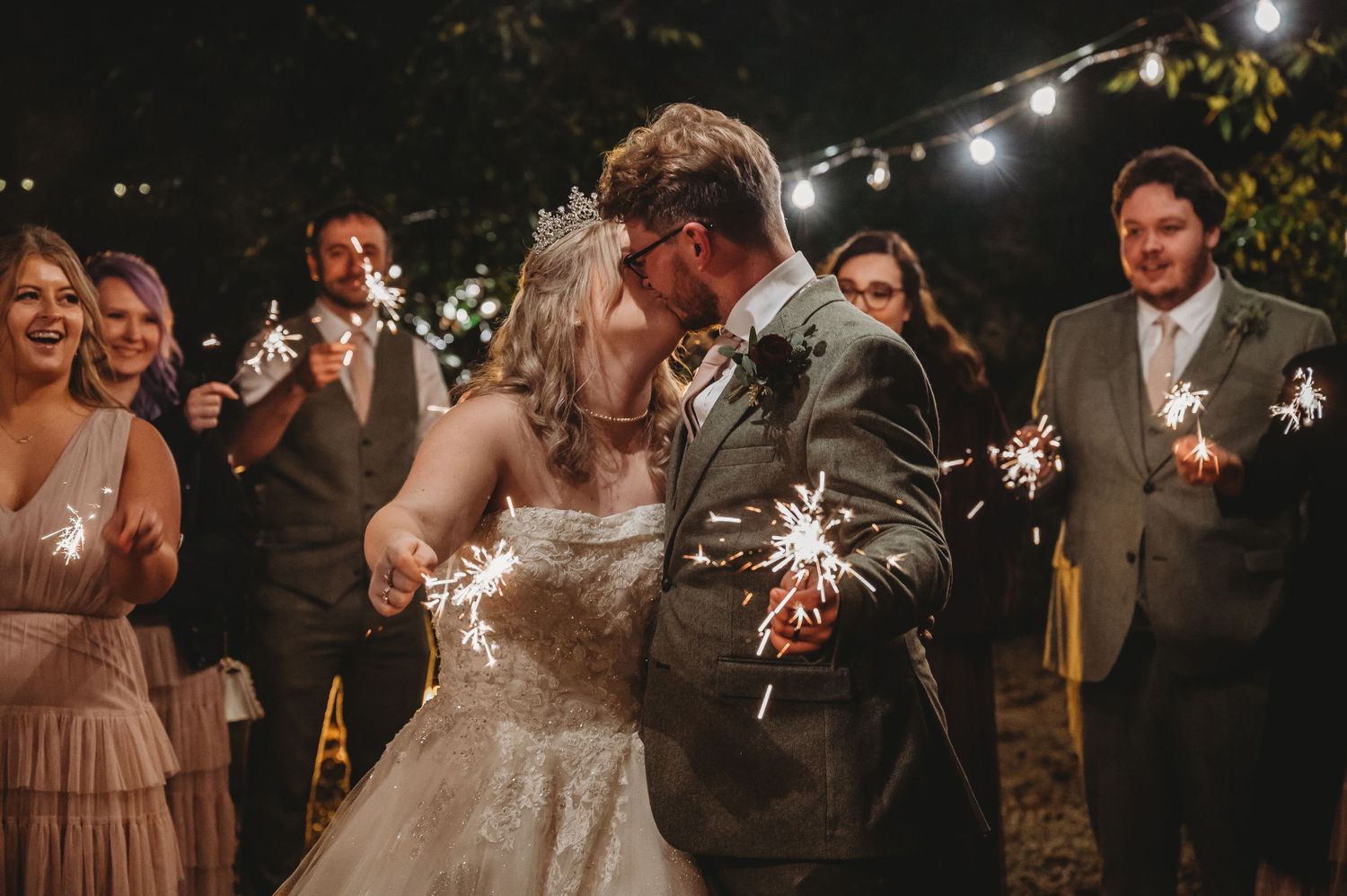 Newlyweds holding sparklers during an evening wedding celebration.