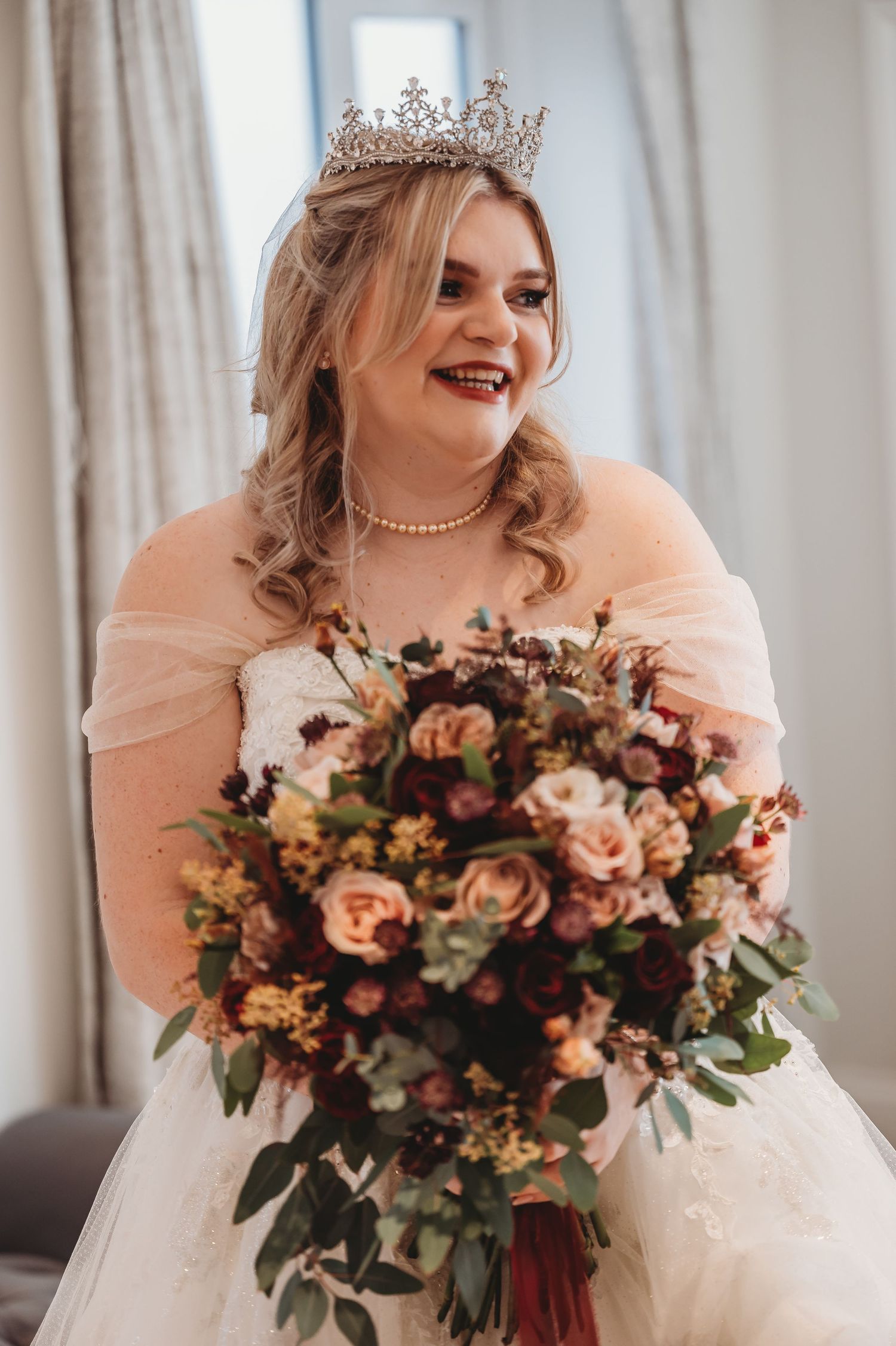 Stunning bridal portrait with crystal crown and peach-toned floral bouquet.