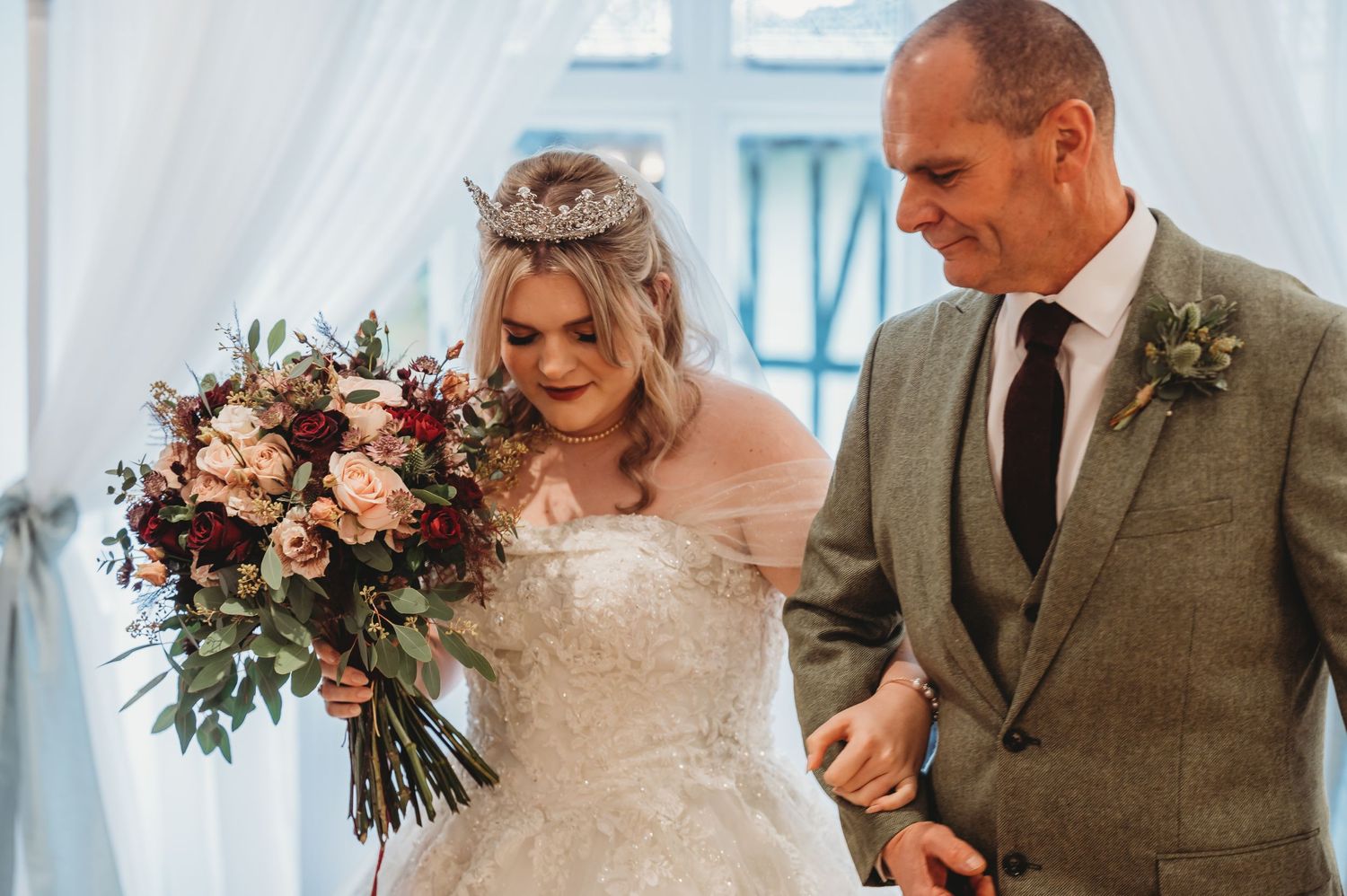 Elegant wedding ceremony scene with beautiful floral bouquet near sheer white drapes.