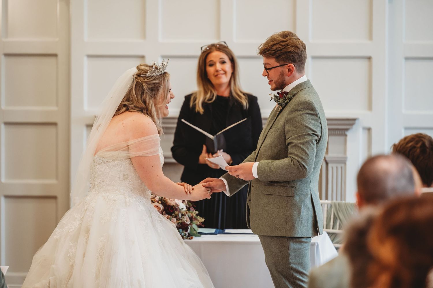 An intimate wedding ceremony moment captured in a bright room with classic white paneled walls.