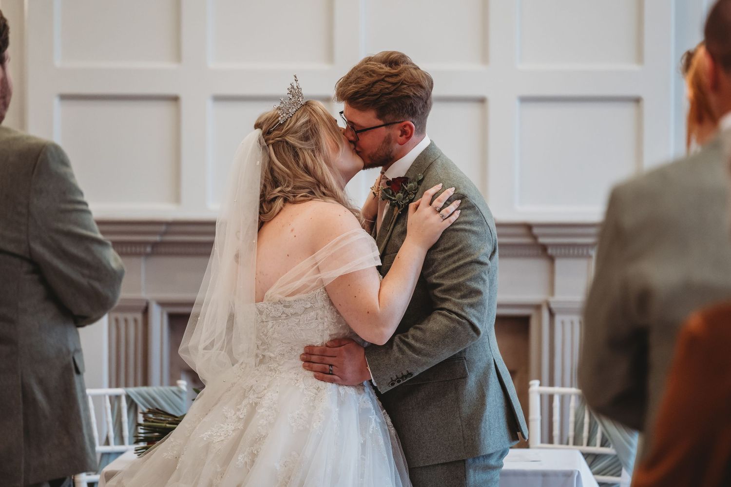 Romantic wedding kiss captured in an elegant white-paneled ceremony venue.