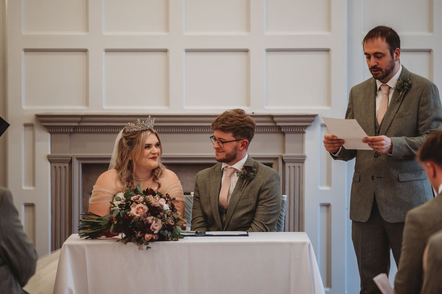 Wedding ceremony moment captured in an elegant white-paneled room with classic decor.