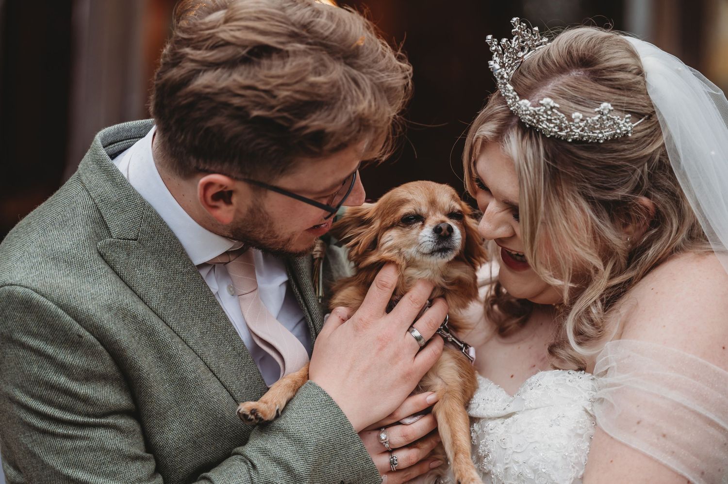 Sweet wedding moment shared with a small dog between the newlyweds.