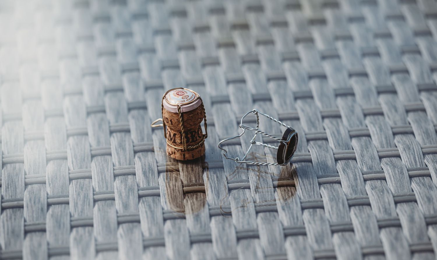 A cork and silver ring sit on a textured woven gray surface in shallow focus detail.