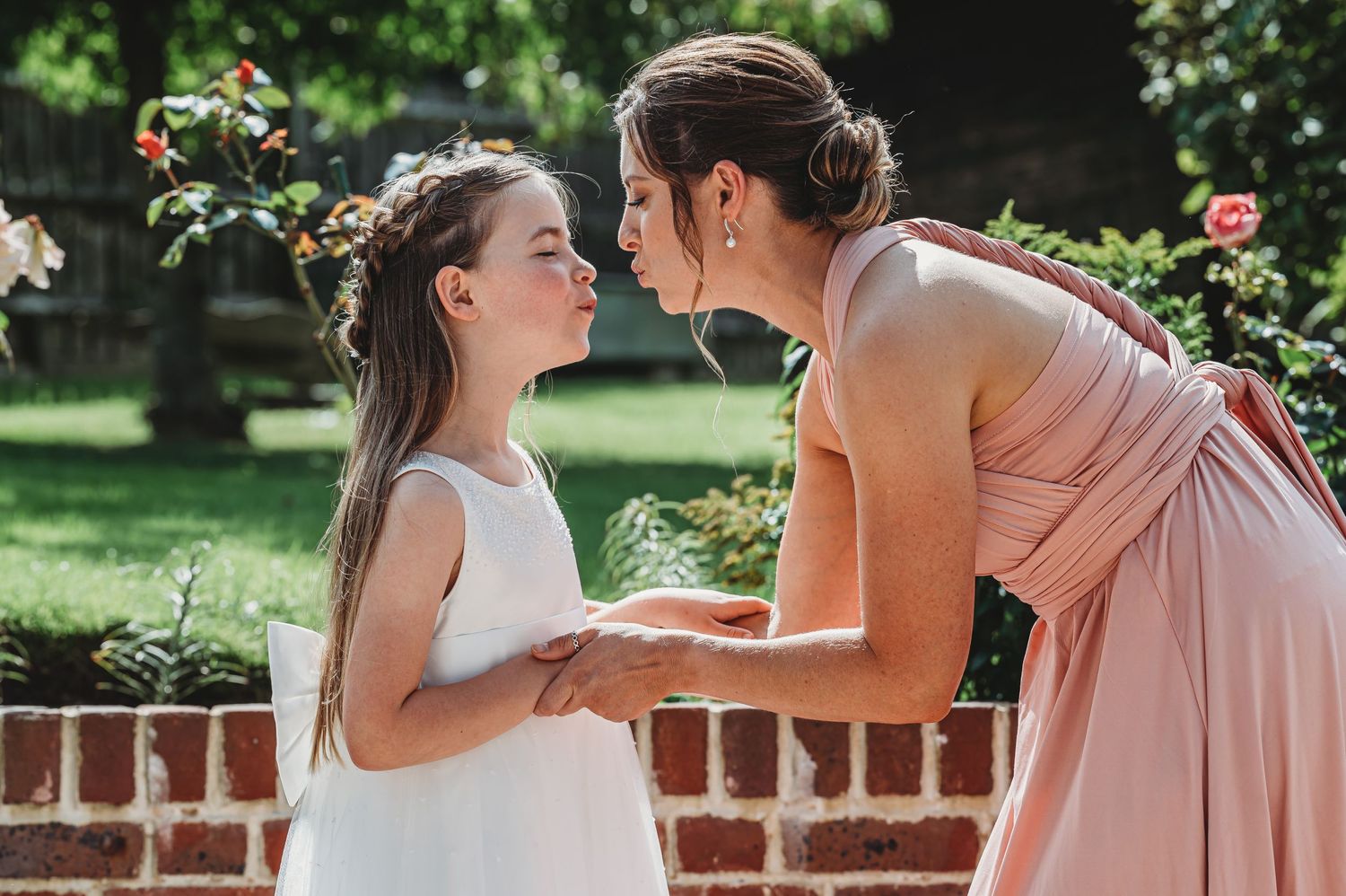 A tender moment is shared between two people in a garden setting with blooming roses.