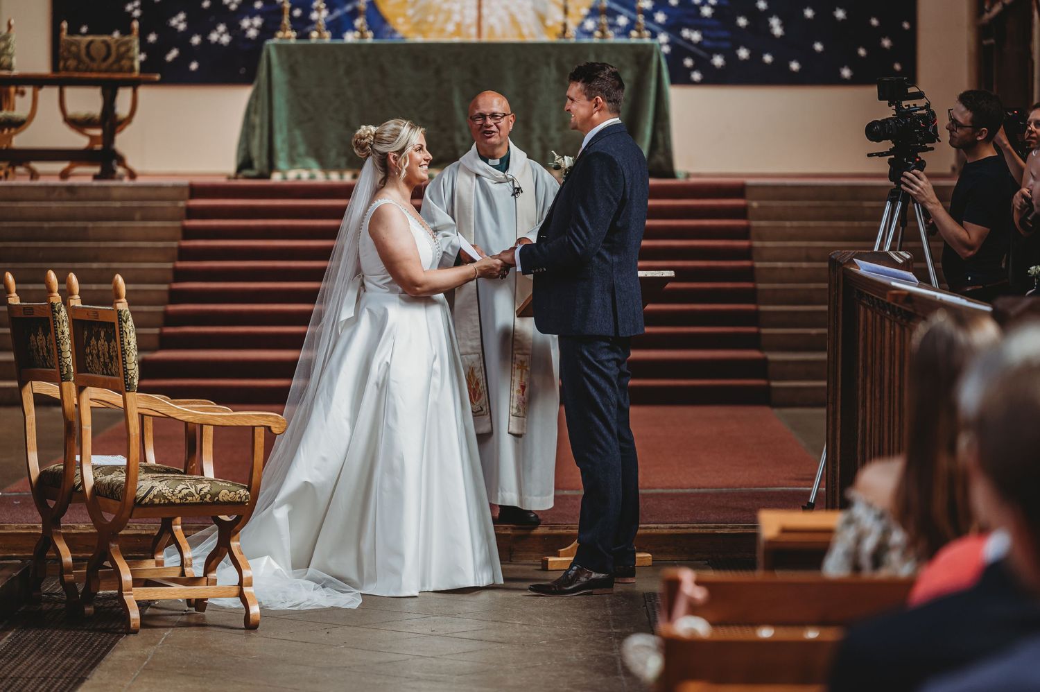 A romantic wedding ceremony takes place in a traditional church with wooden pews and an altar on raised steps.
