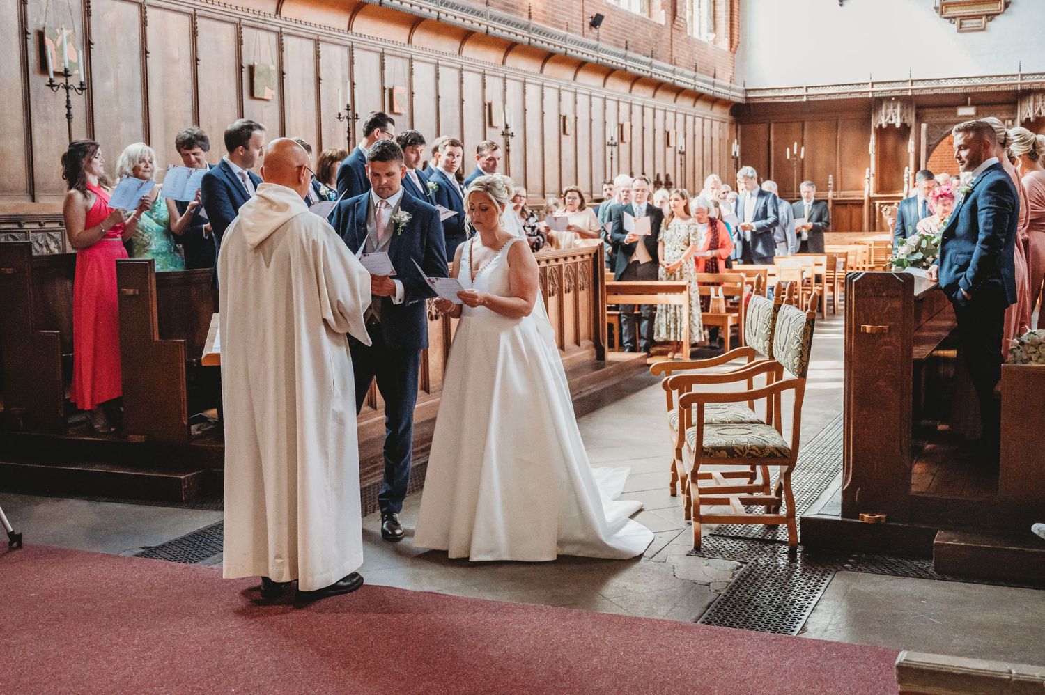 A traditional church wedding ceremony taking place in a beautiful wooden paneled sanctuary with guests looking on.