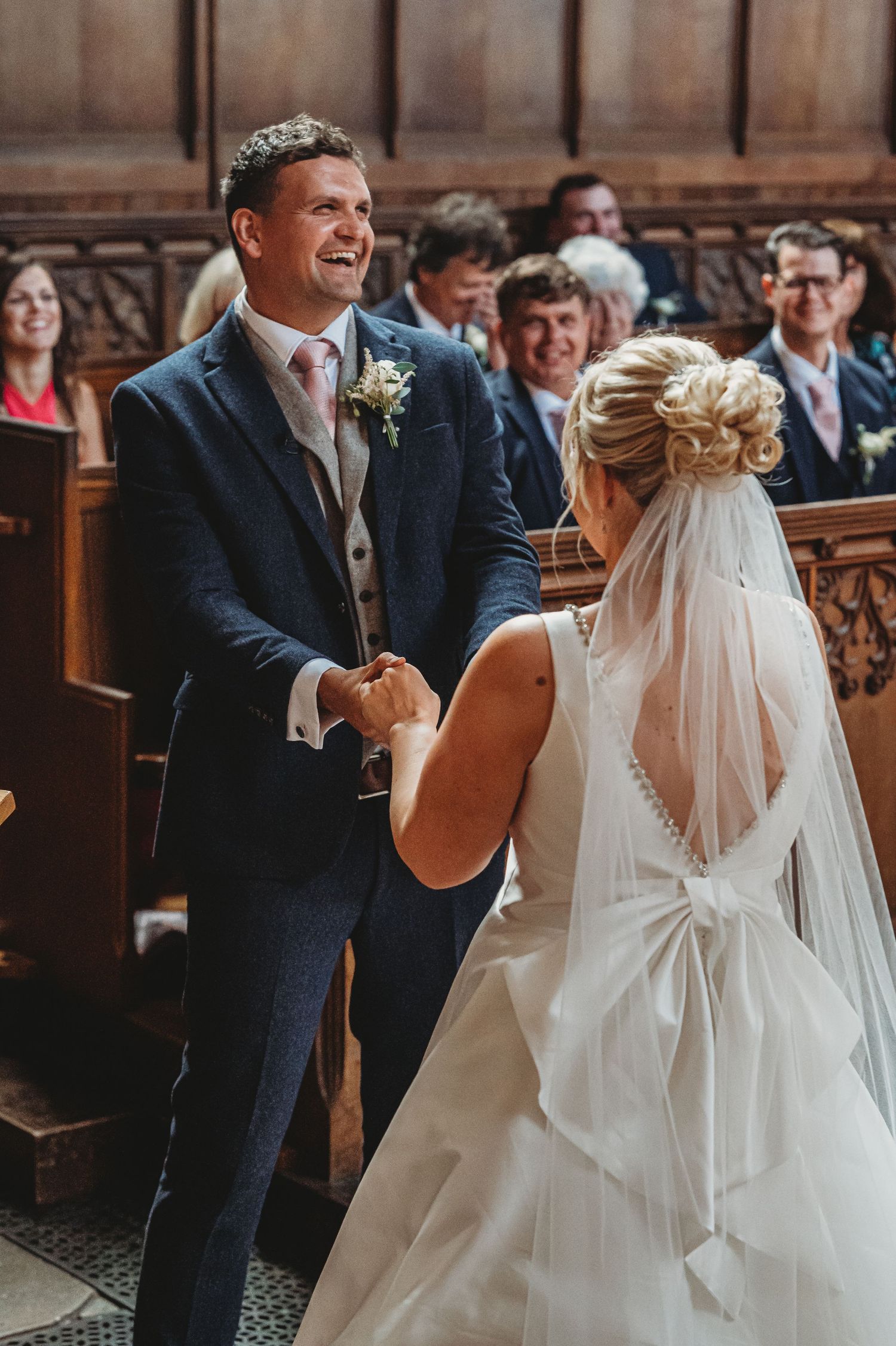 Joyful moment during wedding ceremony as couple shares laughter in ornate traditional church setting.