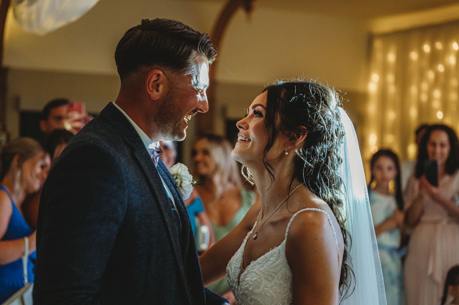 A bride and groom share a joyful moment during their first dance at their wedding reception with guests watching.